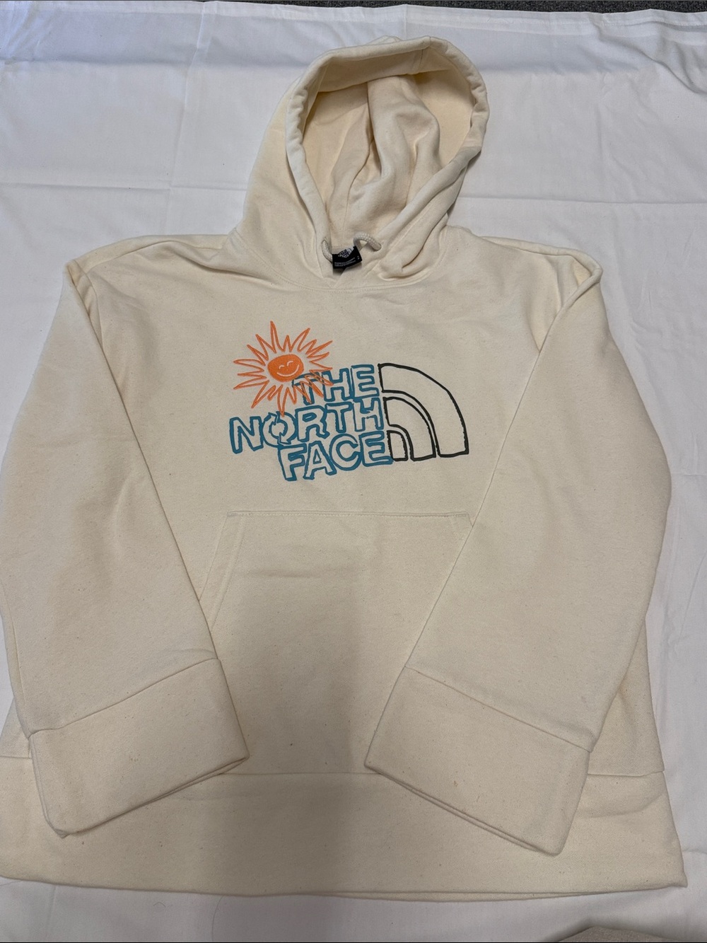 The North Face Cream Hoodie with Orange Sun Graphic and Blue Logo